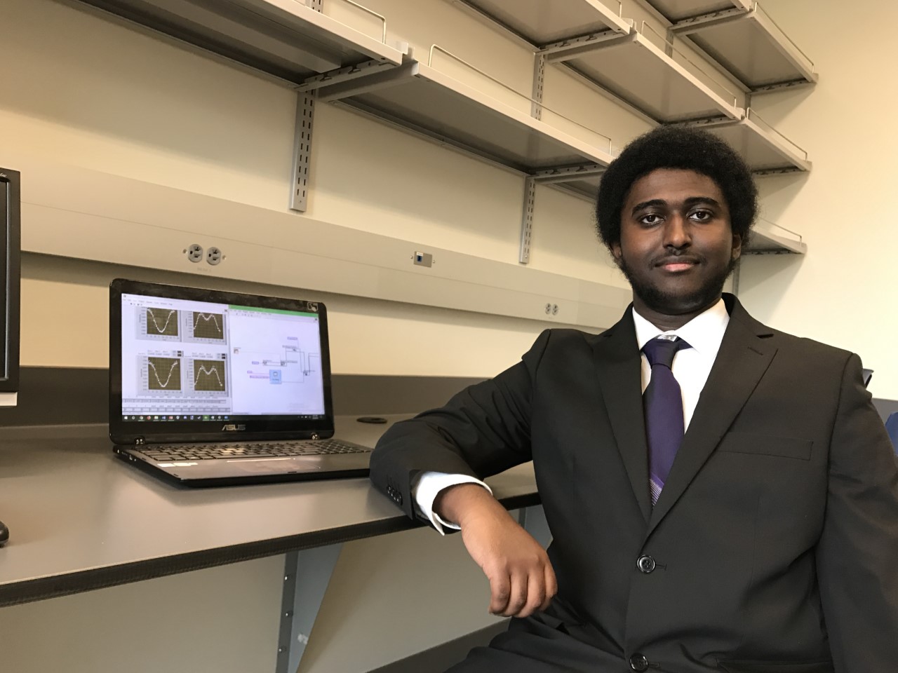 Pictured: Gheleb Netabai posed alongside an open laptop demonstrating his laser data-storage/recall program.